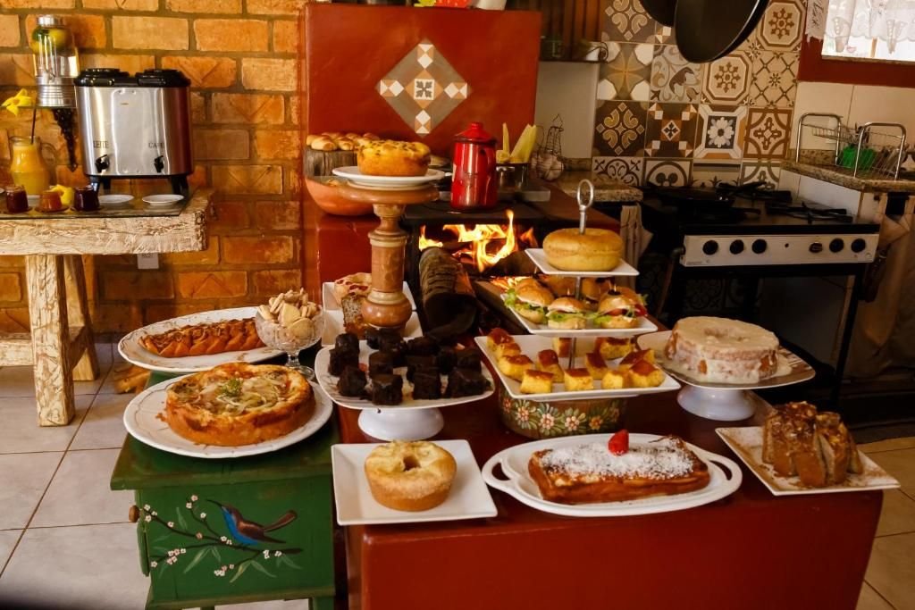 Buffet de café da manhã com tortas, bolos e sanduíches diante do fogão a lenha