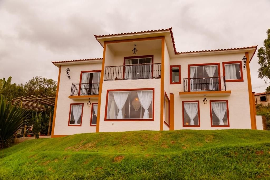 Casarão de dois pavimentos com sacadas de ferro sobre o gramado