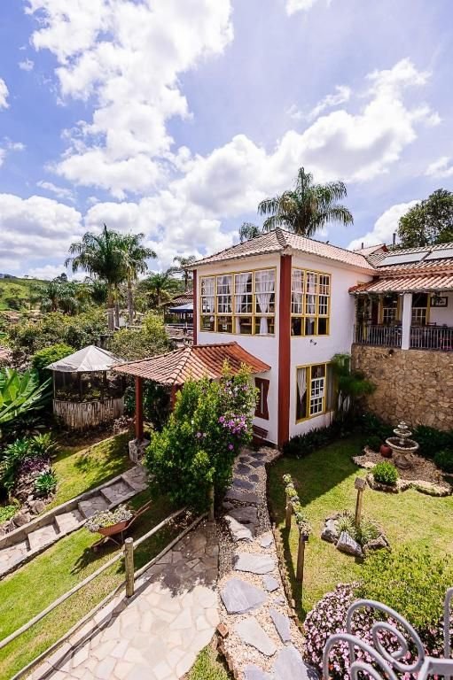 Jardim com caminho de pedras, fonte, palmeiras e bloco de acomodações de janelas amarelas